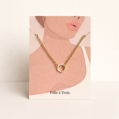 The Zircon Charm NECKLACE displayed on an illustrated Folie a Trois necklace card, the pave zircon circle pendant centered.