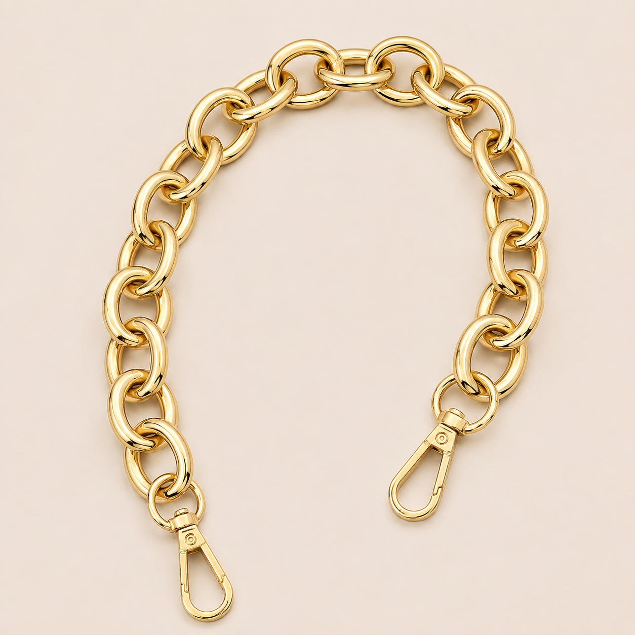 A gold-toned chunky chain link strap with two lobster clasp ends, displayed on a solid pale pink background.
