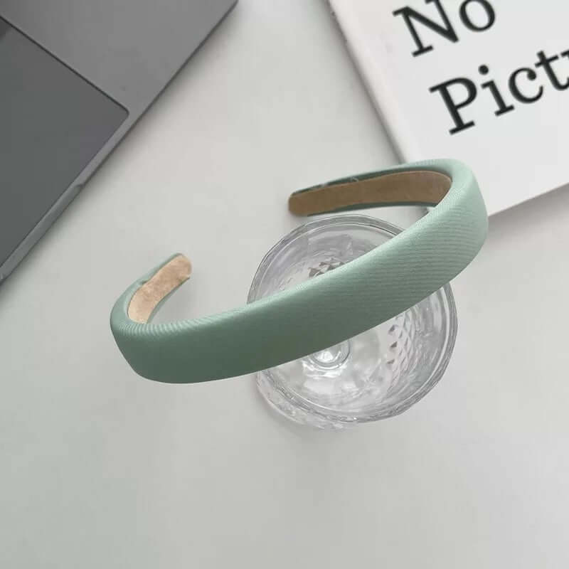 Sage green padded fabric headband styled on a glass tumbler, from a generic headband catalog set.