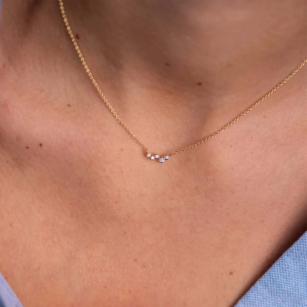 The Hailey NECKLACE in gold worn at the neckline, tiny scattered cubic zirconia stones catching the light on a fine chain.