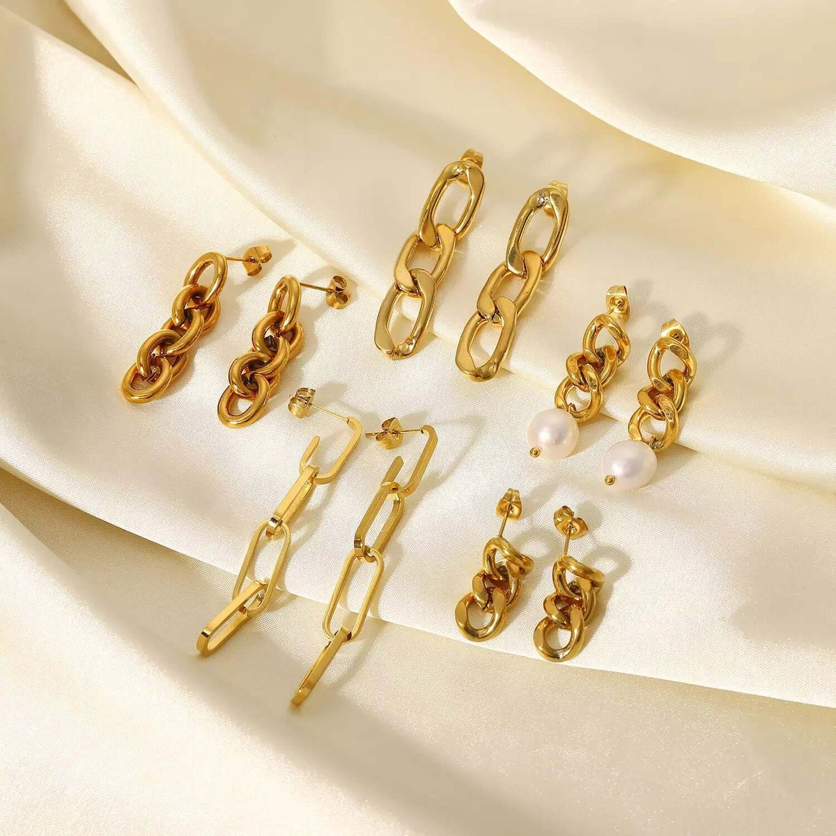 Arranged on satin, Lotte Earrings present their full range of gold chain-link and pearl-drop styles.