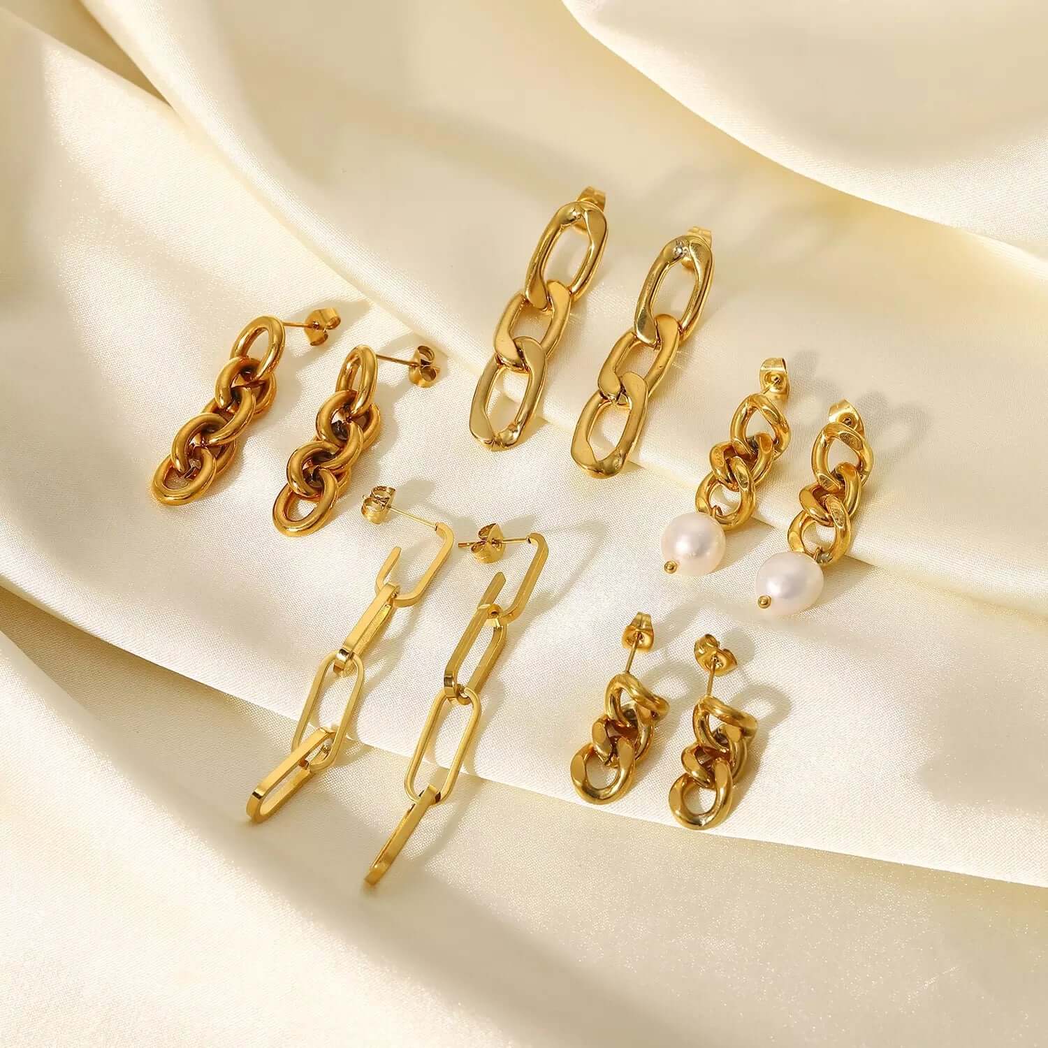 Arranged on satin, Lotte Earrings present their full range of gold chain-link and pearl-drop styles.