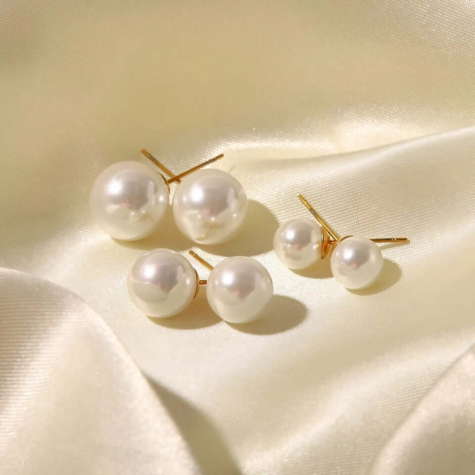 On cream satin, Pearl Me Earrings show their gold posts and three sizes of lustrous round pearls.