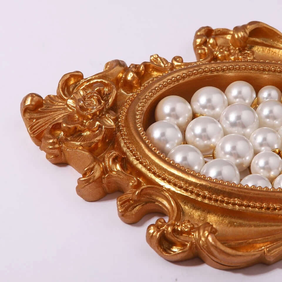 Pearl Me Earrings pile loose pearls inside an ornate gold baroque-style tray for a decorative display.
