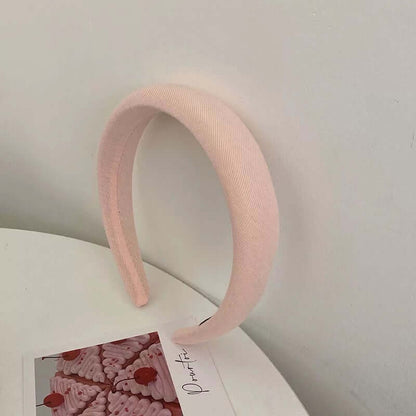 A single pale pink twill ribbed fabric padded headband styled upright near a small photo card.