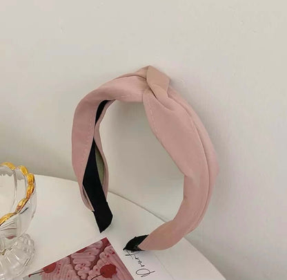 A single dusty pink fabric headband with a knotted top and black lining, styled near a glass dish and photo card.