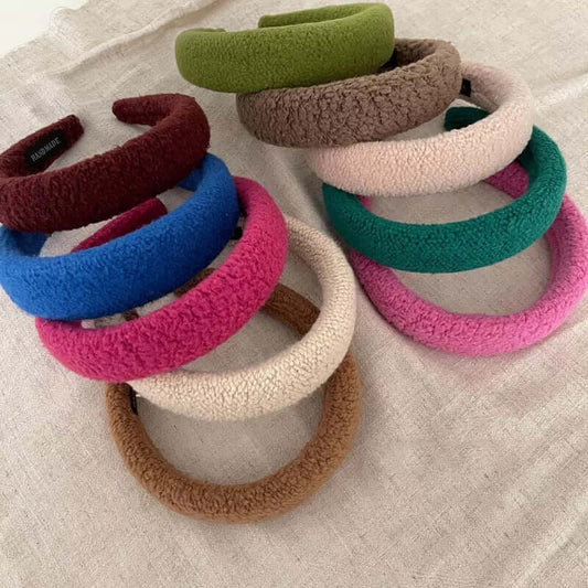 A group of ten Skylar HAIRBAND boucle padded headbands in green, taupe, cream, teal, pink, burgundy, blue and camel laid on linen.