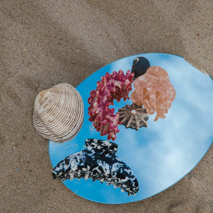 The Soul On The Line HAIR CLIP on a round mirror on sand, styled with a seashell and three other different acetate clips.
